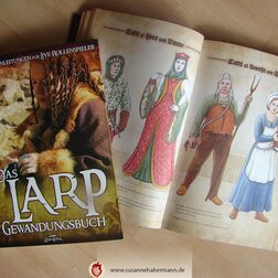 zwei Exemplare von "Das Larp-Gewandungsbuch" - ein Exemplar aufgeschlagen mit Illustrationen